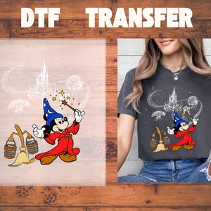 May include: DTF transfer featuring a cartoon image of Mickey Mouse dressed as a wizard, holding a wand with stars, and a castle in the background. The image is on a transparent sheet and also printed on a dark gray t-shirt.
