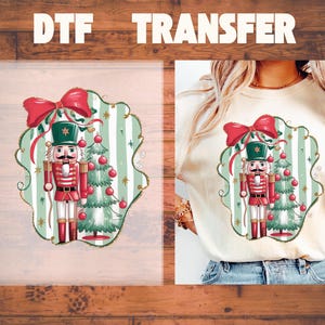 May include: A DTF transfer and a cream-colored t-shirt featuring a graphic of a nutcracker in a red uniform and a green hat standing next to a decorated Christmas tree, all framed by a red bow and light green vertical stripes.
