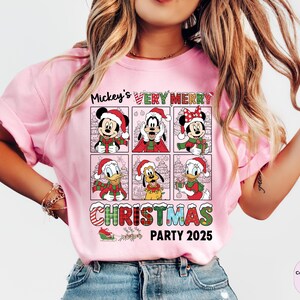 Puede incluir: Camiseta rosa claro con una cuadr&iacute;cula de personajes de Disney con atuendos navide&ntilde;os. La camiseta tiene el texto "Mickey's Very Merry Christmas Party 2025" en una fuente festiva. Tejido Comfort Colors Blossom.