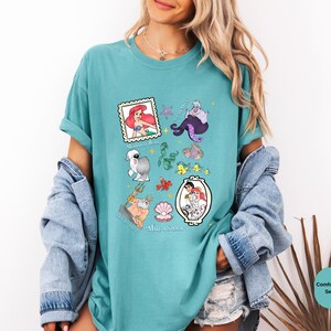 Puede incluir: Una camiseta azul turquesa con un estampado gr&aacute;fico de varios personajes de la pel&iacute;cula de Disney La Sirenita. Los personajes incluyen a Ariel, &Uacute;rsula, Sebasti&aacute;n, Flounder y el pr&iacute;ncipe Eric. El texto "Part of Your World" est&aacute; impreso en la parte inferior de la camiseta.