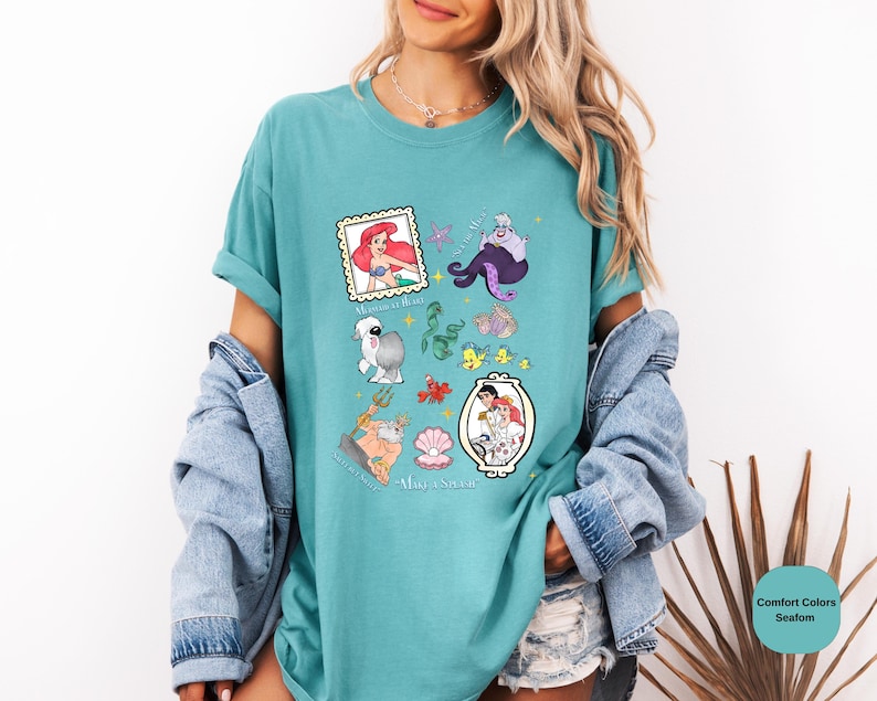 Puede incluir: Una camiseta azul turquesa con un estampado gr&aacute;fico de varios personajes de la pel&iacute;cula de Disney La Sirenita. Los personajes incluyen a Ariel, &Uacute;rsula, Sebasti&aacute;n, Flounder y el pr&iacute;ncipe Eric. El texto "Part of Your World" est&aacute; impreso en la parte inferior de la camiseta.