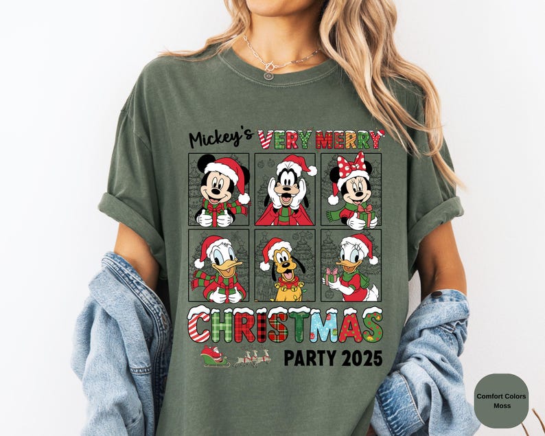 Puede incluir: Camiseta verde oliva con un dise&ntilde;o festivo. Presenta a Mickey Mouse, Minnie Mouse, Goofy, Donald Duck y Pluto, todos con gorros y bufandas de Pap&aacute; Noel. El texto dice "Mickey's Very Merry Christmas Party 2025".