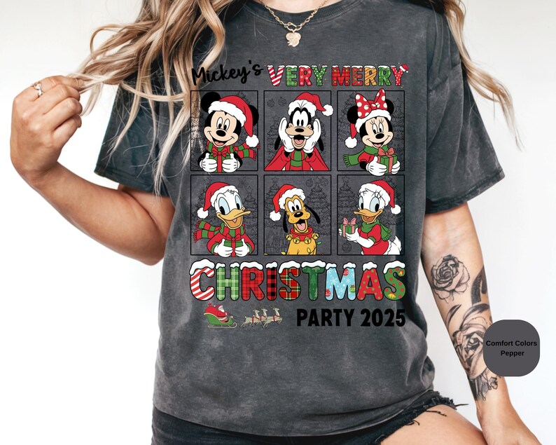 Puede incluir: Camiseta gris oscuro con un dise&ntilde;o navide&ntilde;o que presenta a Mickey Mouse, Minnie Mouse, Goofy, Donald Duck y Pluto, todos con gorros y bufandas de Pap&aacute; Noel. La camiseta incluye el texto "Mickey's VERY MERRY CHRISTMAS PARTY 2025".