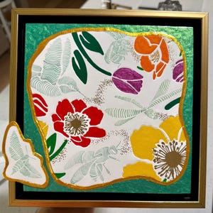 May include: Square framed artwork featuring a floral design with red, yellow, orange, and purple flowers. The artwork has a gold border and a green background. The floral design includes detailed illustrations of bees and dragonflies.