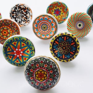May include: Ten colorful ceramic knobs with intricate mandala designs. The knobs are round and have a white background with various colors, including blue, green, orange, red, and yellow.