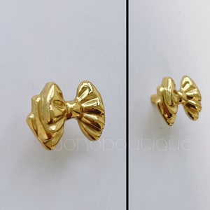 Peut inclure: Bouton de porte en forme de nœud en or avec une finition lisse et brillante.