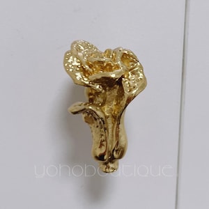 May include: A gold-toned metal flower-shaped cabinet knob.