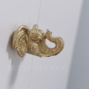 May include: A gold elephant head wall hook. The hook is a decorative piece with a detailed design.