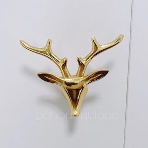 Op de afbeelding: Gouden deurknop in de vorm van een hertenkop met een gedetailleerd ontwerp.