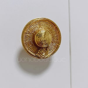 May include: A gold cabinet knob with a textured, circular design. The knob has a central spiral and a floral accent. The text "yohoboutique" is visible on the lower part of the image.
