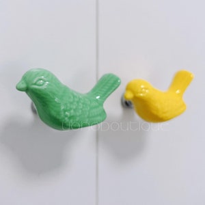 May include: Two ceramic bird-shaped door knobs. One is green and the other is yellow.