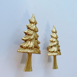 Könnte beinhalten: Zwei goldfarbene Türknauf aus Metall in Form einer Kiefer. Der größere Knauf befindet sich links und der kleinere rechts.