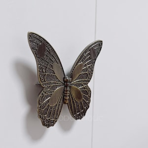 May include: A bronze butterfly-shaped cabinet knob with intricate details.