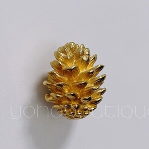 May include: A gold-colored pine cone shaped cabinet knob.