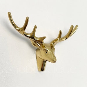 Op de afbeelding: Gouden metalen hertenkop wandhaak met geweien.