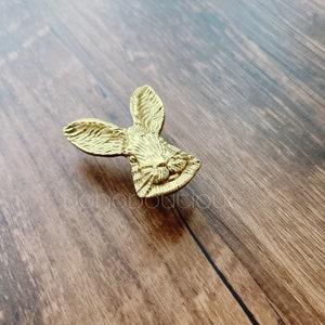 Puede incluir: Un pomo de puerta de color dorado en forma de cabeza de conejo con detalles elaborados.