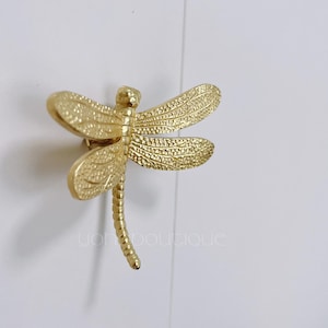 Puede incluir: Pomo de puerta de libélula dorada con acabado texturizado.