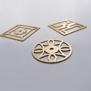 Pode incluir: Três peças decorativas de metal dourado com intrincados desenhos geométricos. As peças são recortadas e têm um acabamento brilhante.