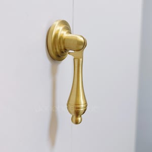 以下が含まれることがあります： 涙滴型のハンドルと丸いベースを持つ金色のキャビネットプル