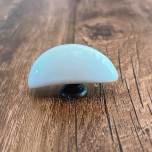 May include: White ceramic half-round cabinet knob with a black metal base.