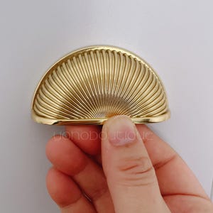 May include: A gold-toned, half-round cabinet knob with a sunburst design.