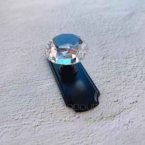 May include: A black cabinet knob with a clear crystal diamond-shaped top.