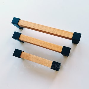 May include: Three wooden cabinet pulls with black end caps. The pulls are different lengths.