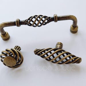 May include: Three antique brass cabinet knobs with a twisted wire design. The knobs are in various sizes and shapes.