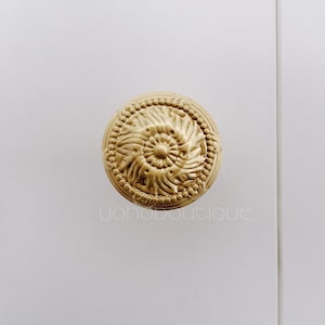 Pode incluir: Um botão decorativo dourado com um design floral detalhado.