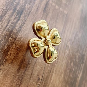 May include: A gold-coloured four-leaf clover shaped cabinet knob.