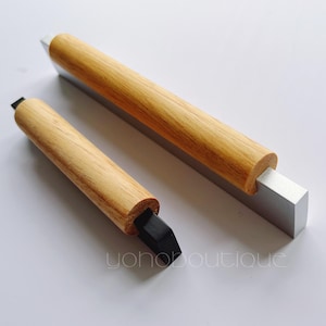 Puede incluir: Dos tiradores de puerta de armario de madera con base de metal plateado. Un tirador tiene una punta de goma negra.