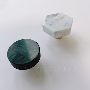 May include: Two marble drawer pulls, one round and green, the other hexagonal and white.