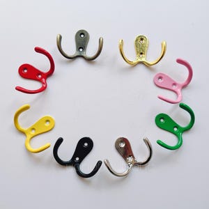 May include: A set of ten double-hook coat hangers in various colours, including red, yellow, green, black, pink, and gold. The hooks are made of metal and have a simple, classic design.