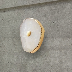 May include: White agate cabinet knob with a gold metal trim. The knob has a round, gold metal accent in the center.