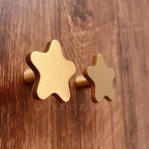 以下が含まれることがあります： 金色の星型のキャビネットノブが2つ。ノブは金属製で、ブラッシュ仕上げです。