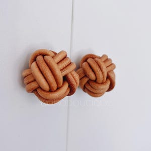 May include: Two brown leather knotted cabinet knobs.