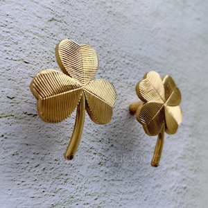 May include: Two gold-colored four-leaf clover shaped door knobs.