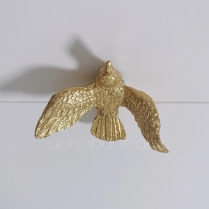 Pode incluir: Puxador de gaveta em forma de pássaro dourado com asas abertas.