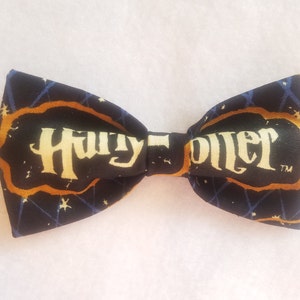 May include: A black bow tie with a gold and white "Harry Potter" logo on a dark blue background with white stars.