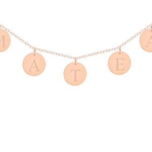 May include: A rose gold necklace with five round charms, each with a letter engraved on it. The letters spell out the word "MATE".