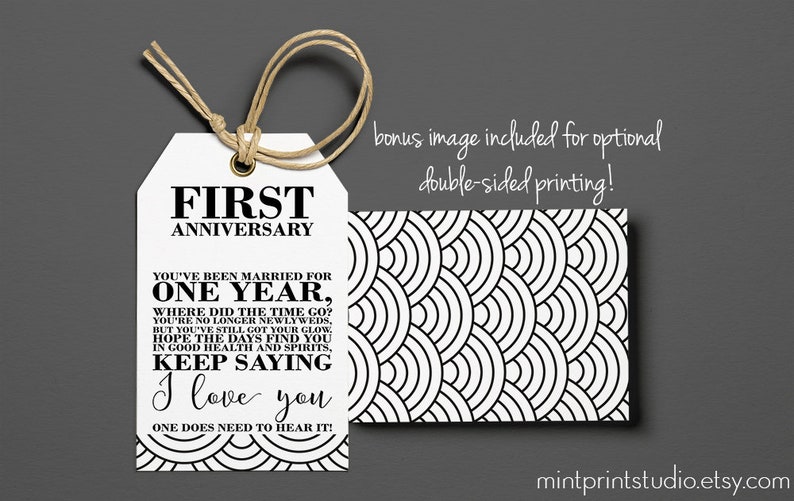 May include: A white gift tag with black text that reads "First Anniversary" and a message about celebrating the first year of marriage. The back of the tag features a black and white geometric pattern.