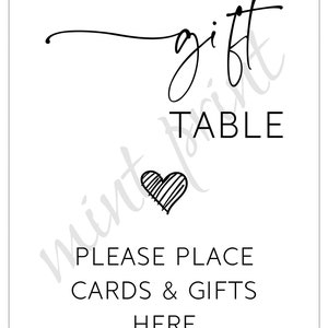 May include: Black and white sign with the text "gift table" and "please place cards & gifts here". A small heart is drawn in the center of the sign.