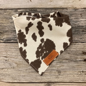 May include: A white and brown cow print bandana with a brown leather tag that says "Willow".