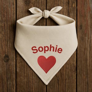 May include: A beige cotton bandana with a red heart and the name "Sophie" embroidered in red.
