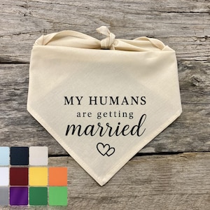 Könnte beinhalten: Cremefarbenes Hundehalstuch mit dem Text "MY HUMANS are getting married" in schwarzer Schrift. Zwei Herzen befinden sich unter dem Text. Das Halstuch ist oben gebunden. Unten ist eine Farbkarte.