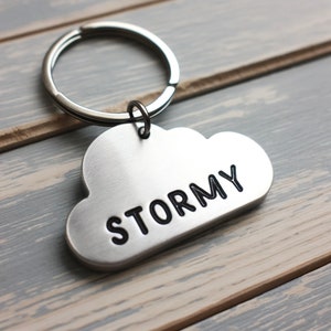 May include: Silver cloud-shaped keychain with the word "STORMY" engraved in black lettering.