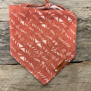 May include: A red bandana with a white geometric pattern and the word "DUKE" on a brown leather tag.