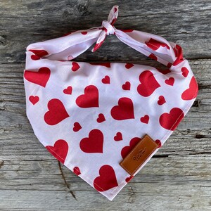 Puede incluir: Bandana blanca con estampado de corazones rojos y nudo. La bandana presenta un patr&oacute;n repetido de corazones rojos sobre fondo blanco. Una peque&ntilde;a etiqueta de cuero marr&oacute;n con la palabra "Willow" est&aacute; cosida en la esquina.