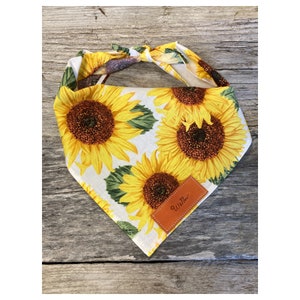 May include: White dog bandana with a sunflower print and a brown leather patch that says "Willow".