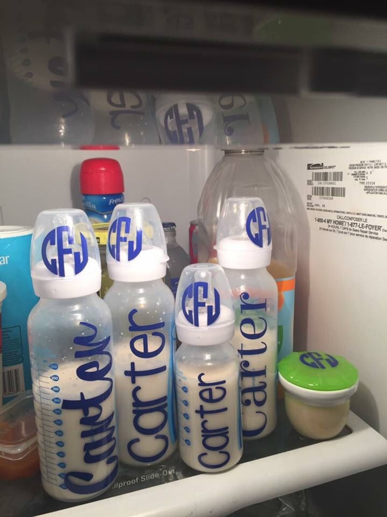 Peut inclure: Quatre biberons en verre transparent avec des &eacute;tiquettes bleues et blanches indiquant "Carter" et "Just Like" dans un r&eacute;frig&eacute;rateur. Les biberons sont remplis d'un liquide blanc. Il y a un r&eacute;cipient vert avec un couvercle dans le coin inf&eacute;rieur droit.